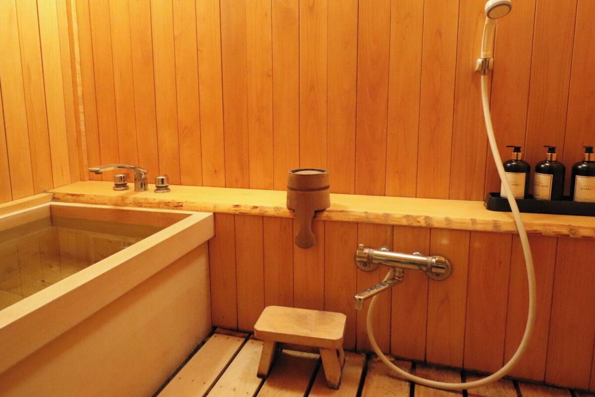 A wooden-paneled bathroom with a bathtub, a shower, and a small stool.