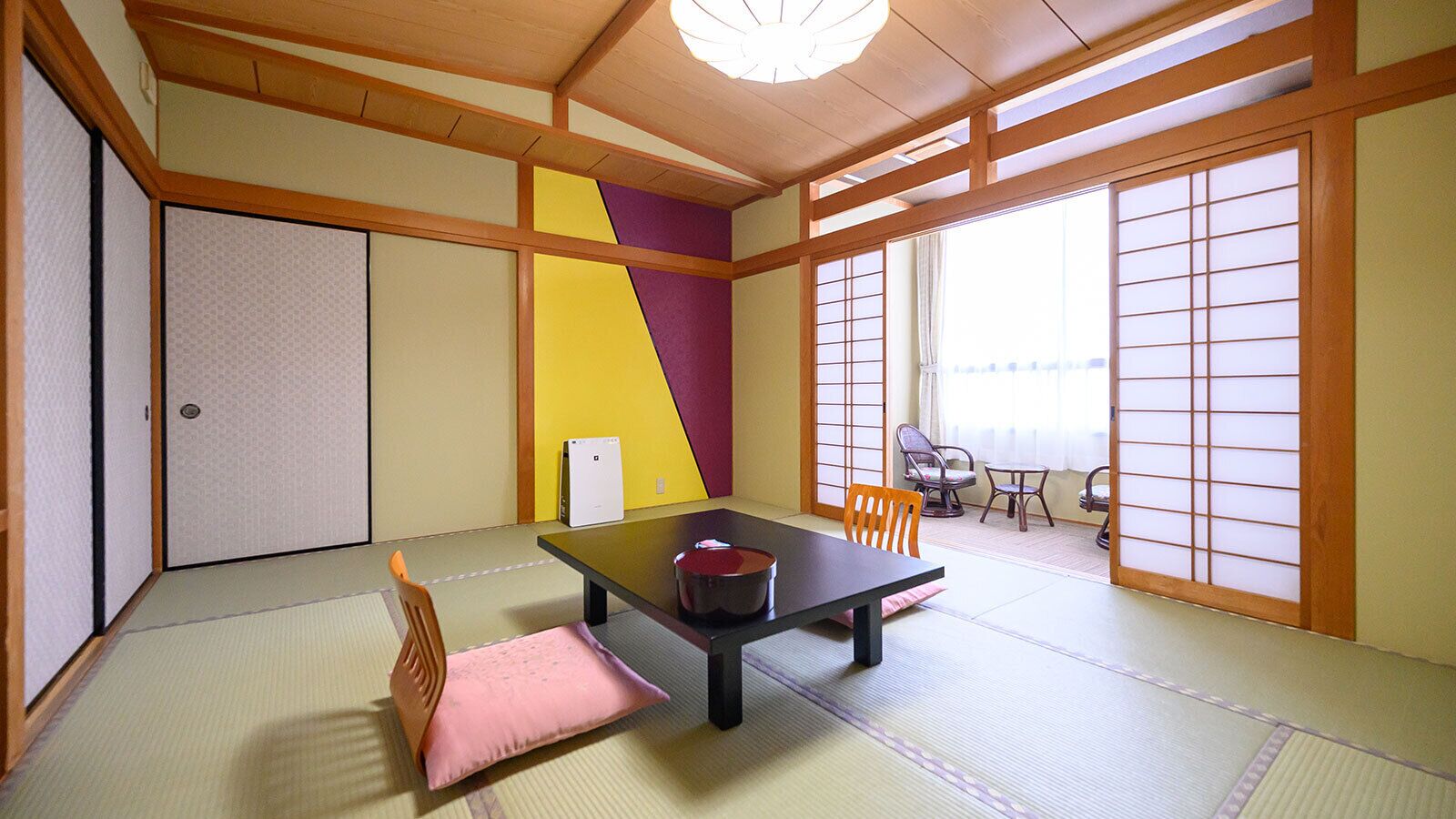 Una estança amb matalassos de tatami, una taula baixa, cadires i una porta corredissa.