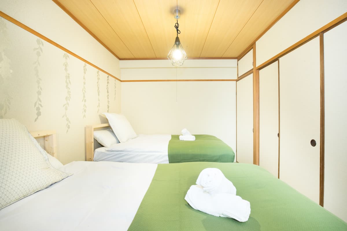 Habitación de hotel con dos camas, techo de madera y una lámpara colgante.