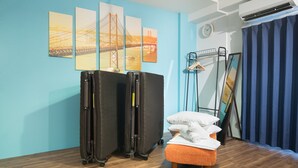 A room with a bed, a suitcase, a mirror, and artwork on the wall. - Namba Hara Apartment (Osaka)