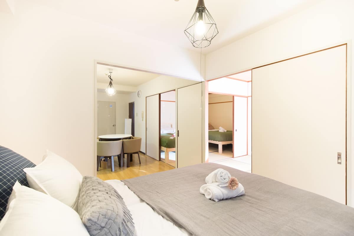 Un dormitorio con cama, almohadas, una mesita de noche y una lámpara colgante.