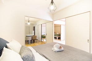 A bedroom with a bed, pillows, a bedside table, and a hanging light fixture.