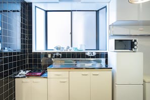 A compact kitchen with a window, a sink, a microwave, and a refrigerator.