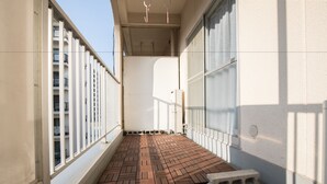 A narrow balcony with a wooden floor, white railings, and a concrete step. - Namba Hara Apartment (Osaka)