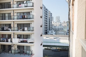 A multi-story residential building with balconies, a parking area, and a view of a cityscape including a building labeled "HOZAN".