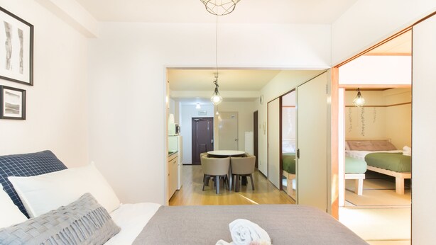 A hotel room with a bed, a small dining table, and a separate sleeping area. - Namba Hara Apartment (Osaka)