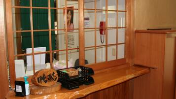 A wooden counter with a wooden plaque, a black telephone, a small black box, and a bottle of hand sanitizer.