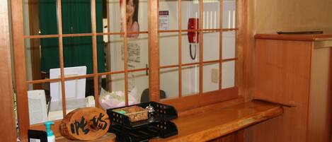 A wooden counter with a wooden plaque, a black telephone, a small black box, and a bottle of hand sanitizer.