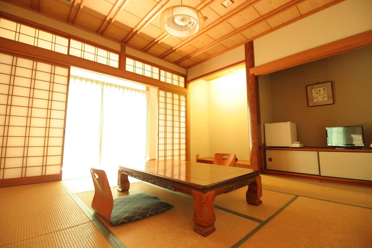 Una habitación japonesa tradicional con suelo de tatami, una mesita baja y puertas correderas.