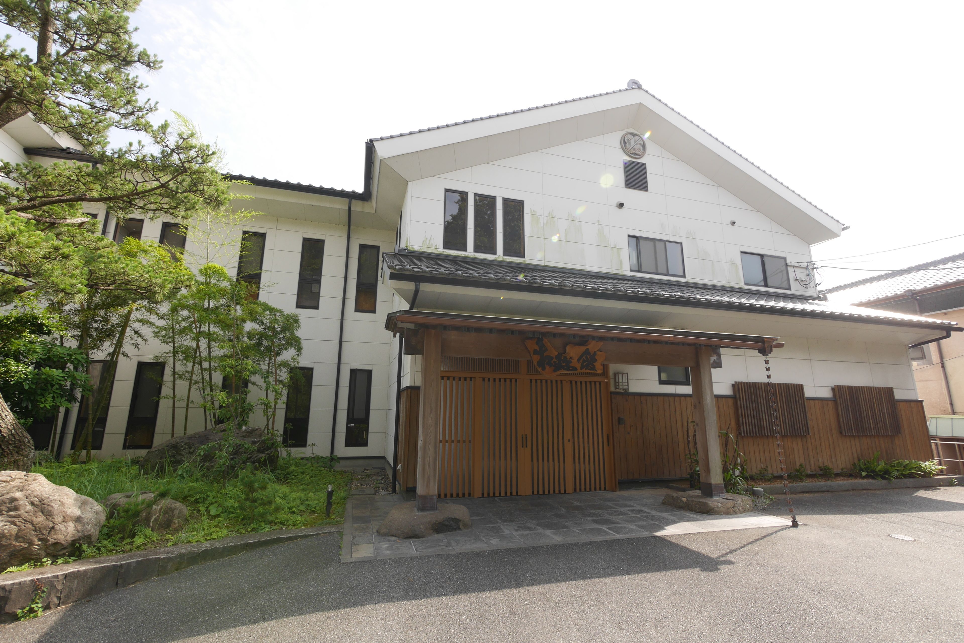 A two-story building with a traditional Japanese entrance, a covered porch, and a stone pathway leading to the entrance.