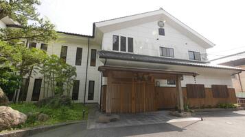 A two-story building with a traditional Japanese entrance, a covered porch, and a stone pathway leading to the entrance.