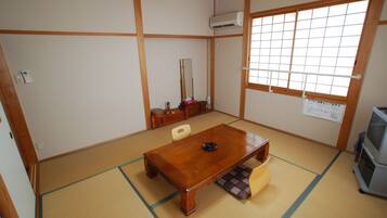 A traditional Japanese room with tatami flooring, a wooden table, a television, and a shoji screen.