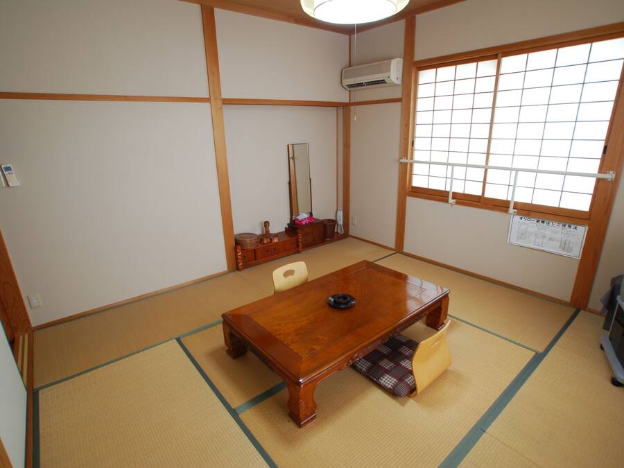 A traditional Japanese room with tatami flooring, a wooden table, a television, and a shoji screen.