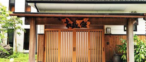 Un portón tradicional japonés con listones de madera y un letrero en la parte superior.