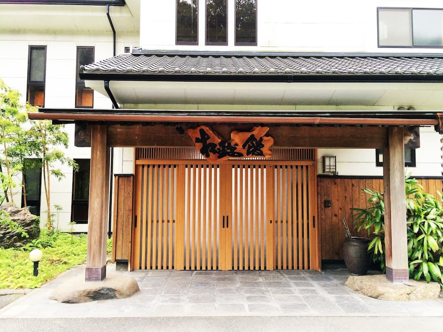 Une porte japonaise traditionnelle, faite de lattes de bois, avec une enseigne au-dessus.