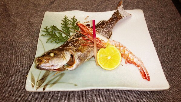 Prato com peixe, fatia de limão e acompanhamentos.