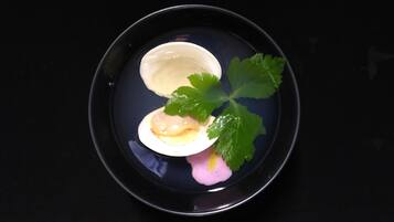 A plate with a white bowl containing a pink substance, a green leaf, and a small white object.