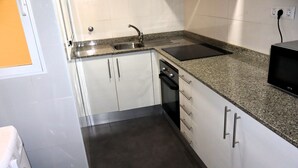 A compact kitchen with a built-in dishwasher, a stainless steel sink, and a microwave. - Los Monegros (Peñiscola)