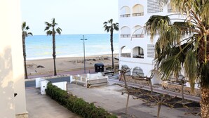 A beachfront hotel with a view of the ocean, palm trees, and a parking area. - Los Monegros (Peñiscola)