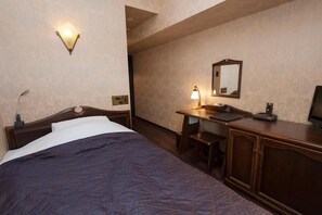 Habitación de hotel con cama, escritorio, silla, lámpara de escritorio, espejo y televisor.