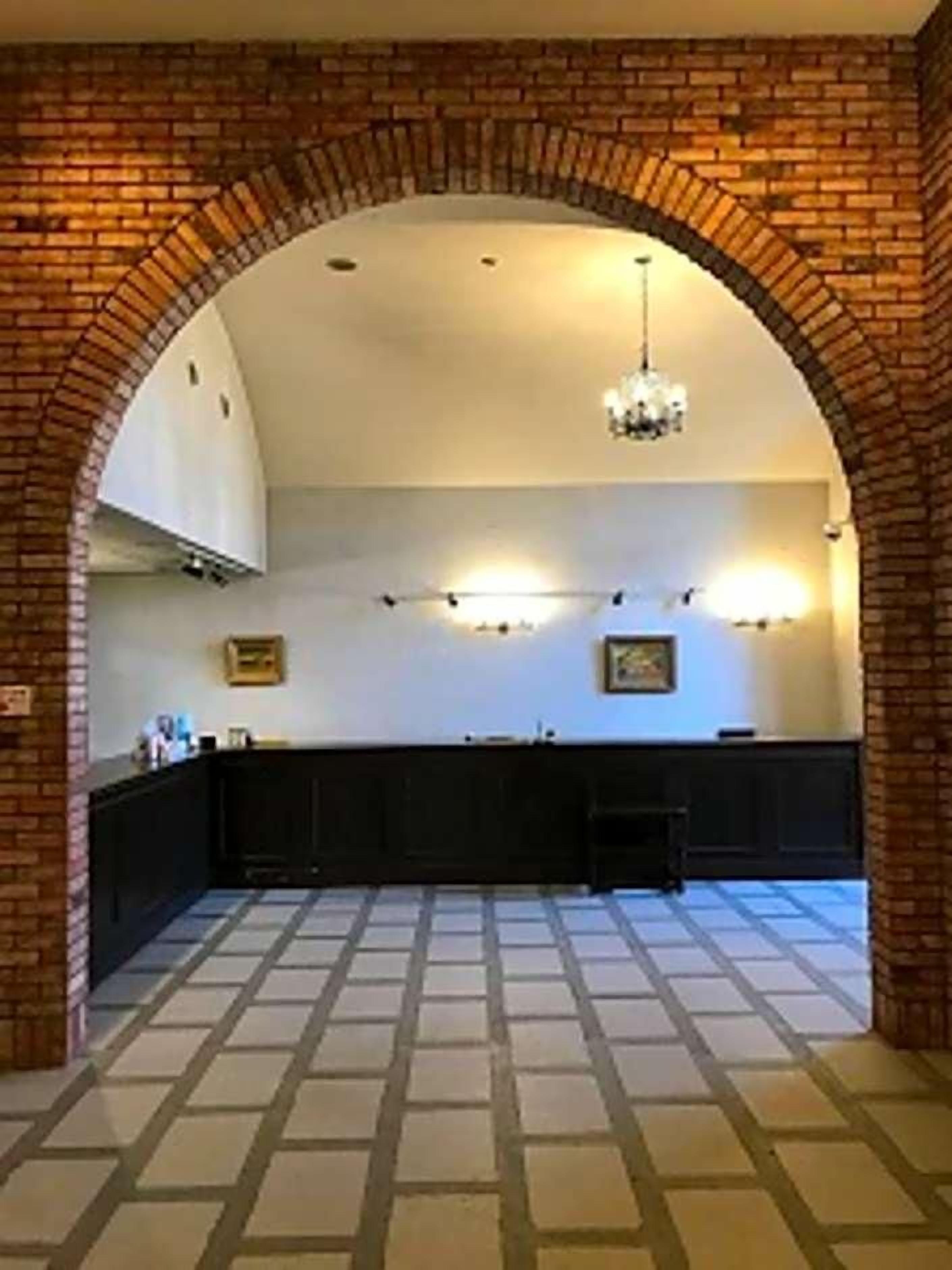 An interior space with a brick archway leading to a kitchen area with a counter and cabinets.