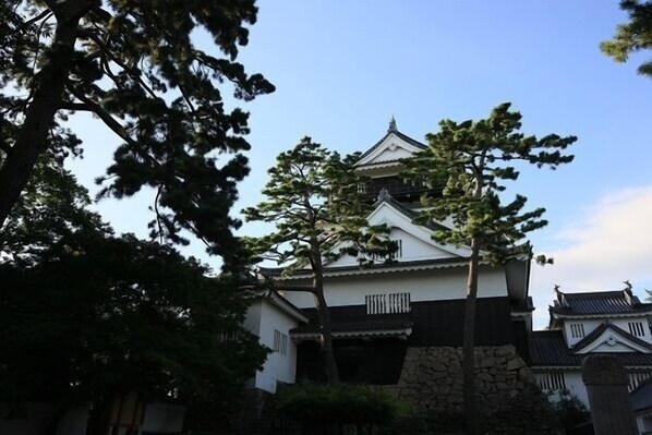Ein traditionelles japanisches Gebäude mit einem markanten, zentralen Turm, umgeben von Bäumen.