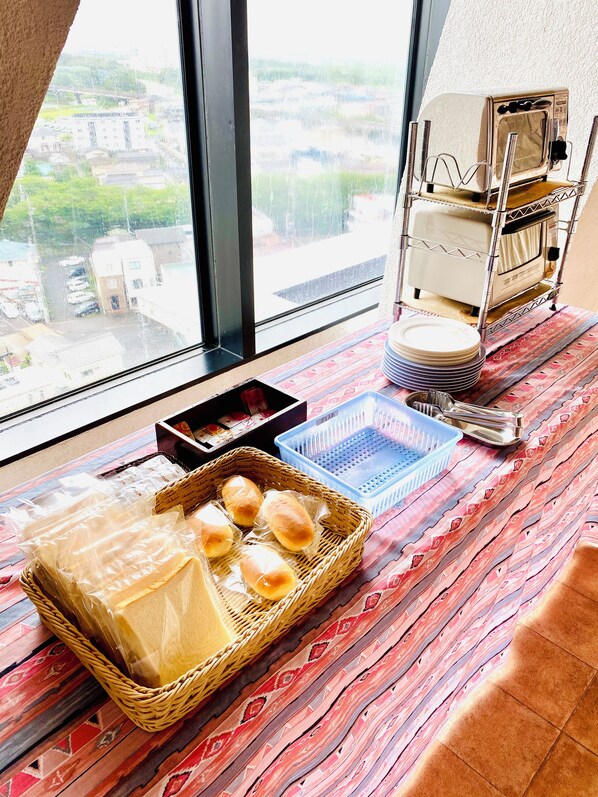 Uma área de refeições com mesa posta para uma refeição, uma torradeira e vista para o exterior.