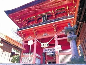 Un edificio tradicional de color rojo con tejado de tejas, un pilar de piedra y un letrero.