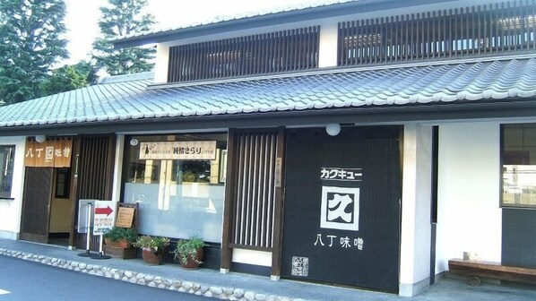Un bâtiment japonais traditionnel, doté d’un toit recouvert de tuiles et d’une enseigne indiquant qu’il s’agit d’un restaurant.