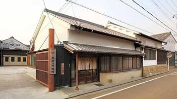A traditional Japanese building with a tiled roof, a wooden entrance gate, and a signboard.
