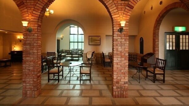 A spacious indoor area with brick arches, tables, and chairs arranged for dining or socializing. - Okazaki Ohwa Hotel (Okazaki)
