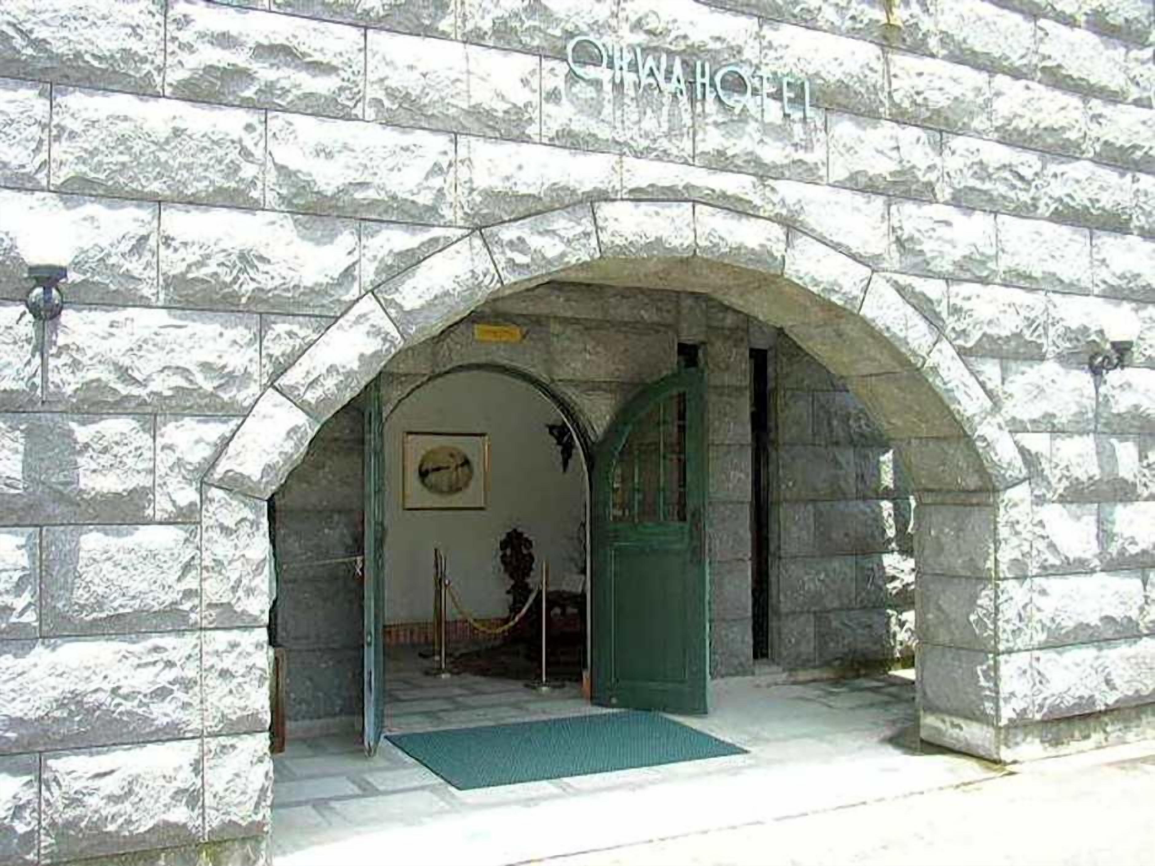 An arched stone entrance to a building labeled 'CHINA HOTEL' with a green door and a doormat.