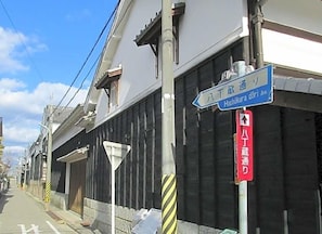 A street view with a blue directional sign for Hachikura Dori and a red sign indicating a one-hour parking limit.