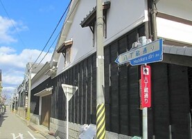 Vista de la calle con un letrero azul que indica Hachikura Dori y un letrero rojo que muestra un límite de estacionamiento de una hora.