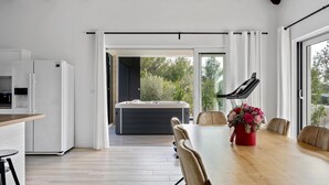 A modern kitchen with a built-in refrigerator, a dining area with a wooden table and chairs, and a hot tub in the background. - Lovely home in Dubrava with sauna (Dubrava)