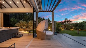 A modern outdoor seating area with a covered chair and a hot tub. - Lovely home in Dubrava with sauna (Dubrava)