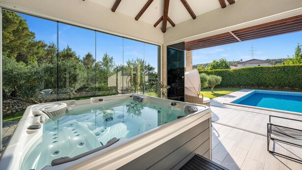 A hot tub with a glass enclosure, a pool, and a view of a garden and hills. - Lovely home in Dubrava with sauna (Dubrava)