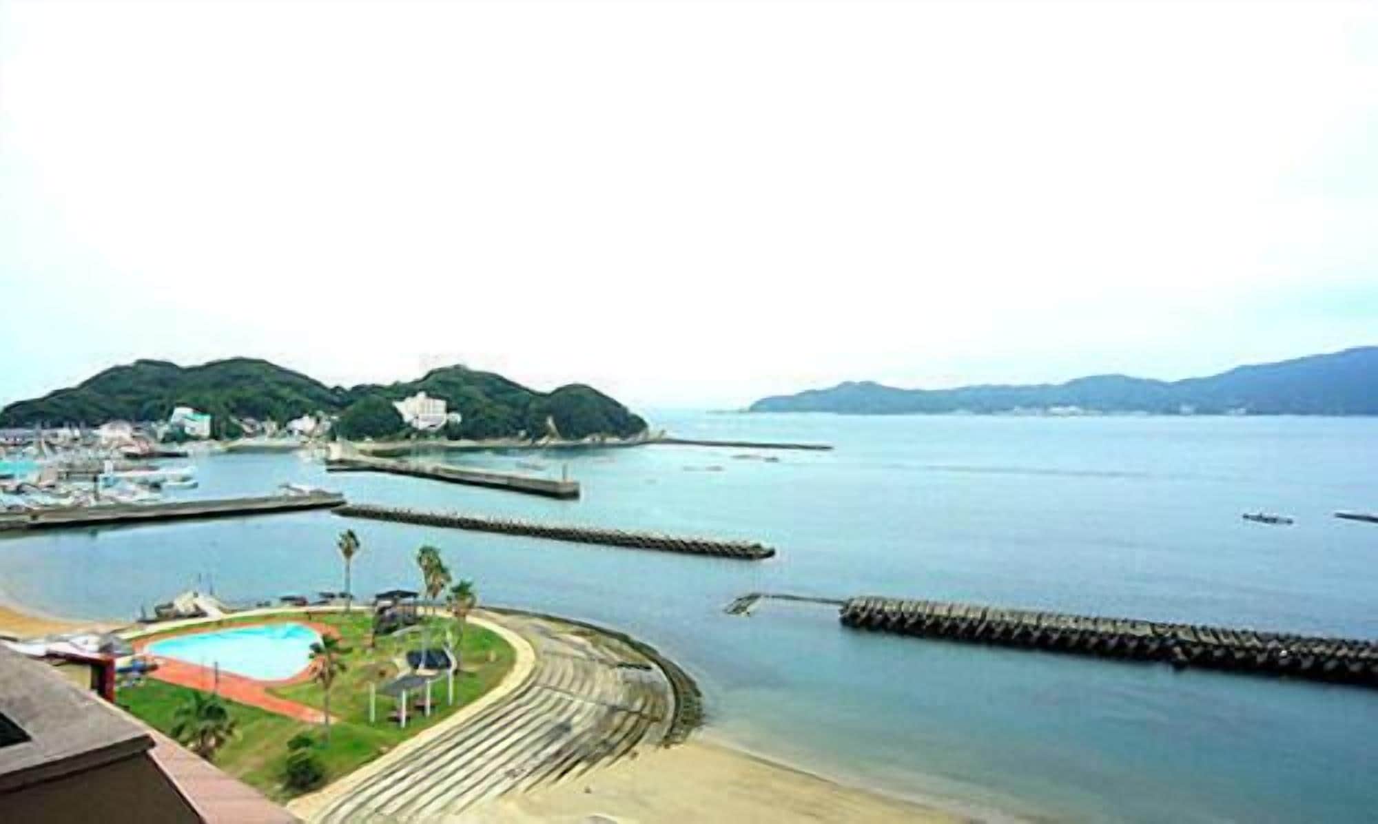 A coastal area with a swimming pool, a beach, and a pier extending into the water.