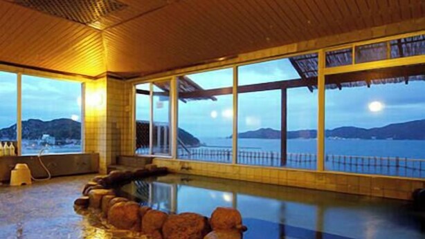 An indoor swimming pool with a view of the sea, wooden ceiling, and stone border. - Nakamuraya (Toba)