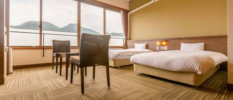 A hotel room with a large window, a bed, a chair, and a carpeted floor.