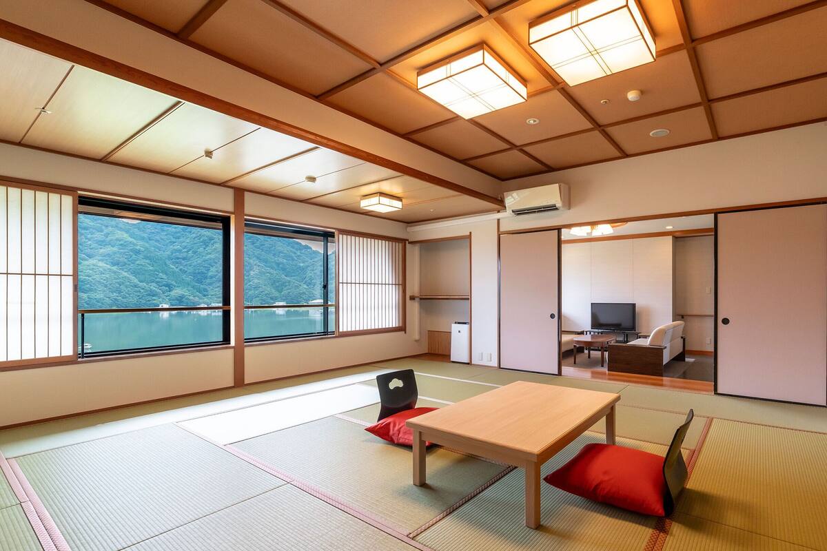 A traditional Japanese room with tatami flooring, a wooden table, and a television.