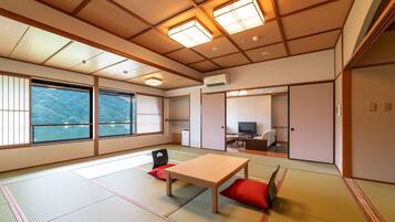 Een traditionele Japanse kamer met tatami vloerbedekking, een houten tafel en een televisie.