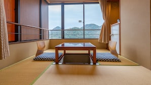 A traditional Japanese room with tatami flooring, a low wooden table, and a view of mountains through large windows.