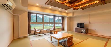 Una habitación con suelo de tatami, televisor, mesa y sillas.