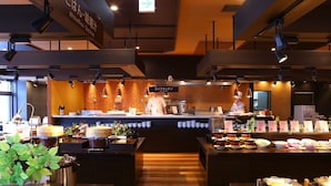 A restaurant interior with a buffet setup, chefs at work, and a variety of food items displayed.