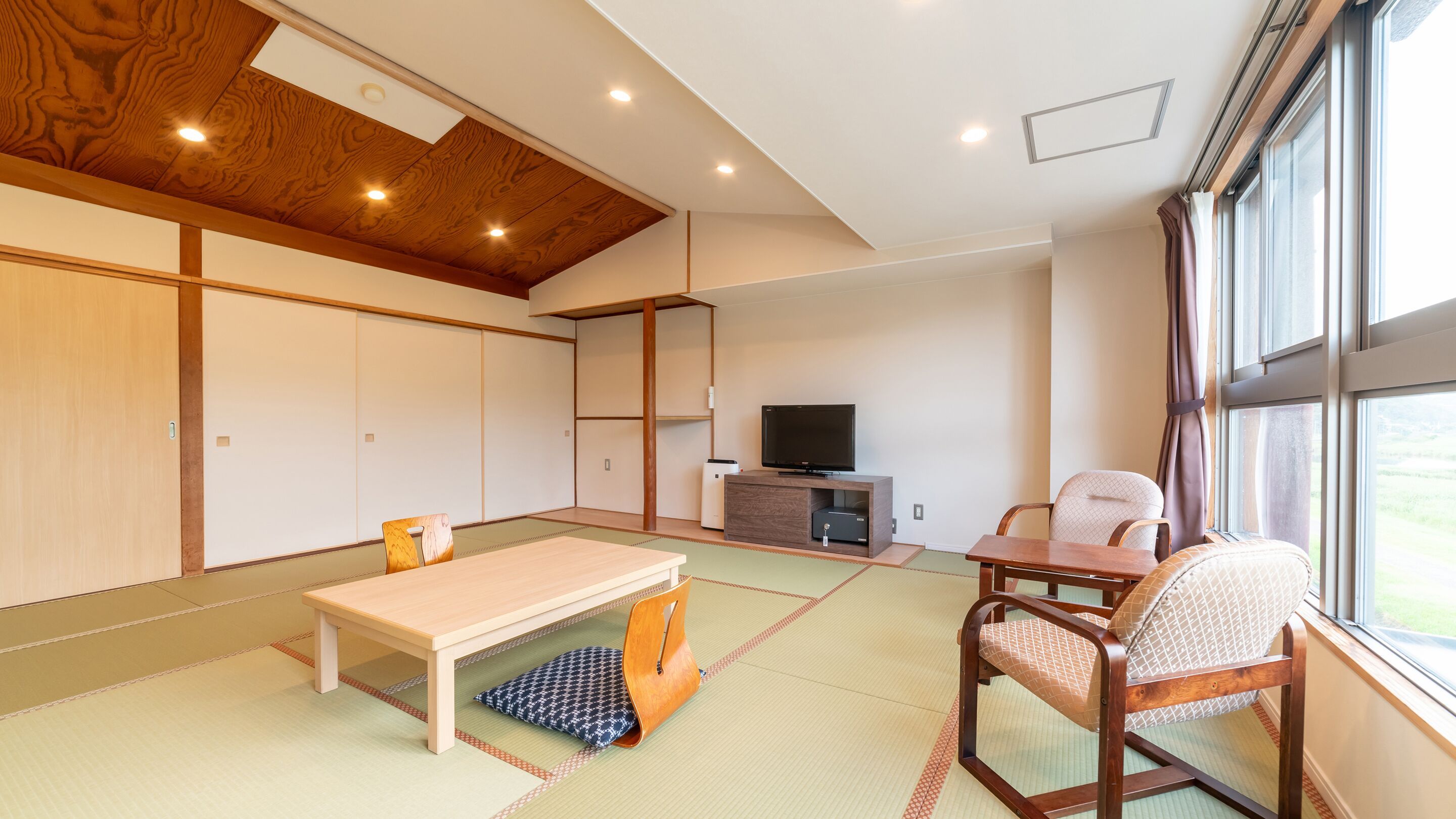 Een traditionele Japanse woonkamer met tatami vloerbedekking, een lage houten tafel, een televisie en schuifdeuren.