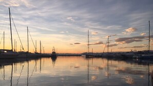 A marina with multiple sailboats docked at sunset.