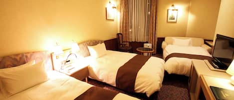 Habitación de hotel con dos camas, un escritorio, una silla, un televisor y una ventana con cortinas.