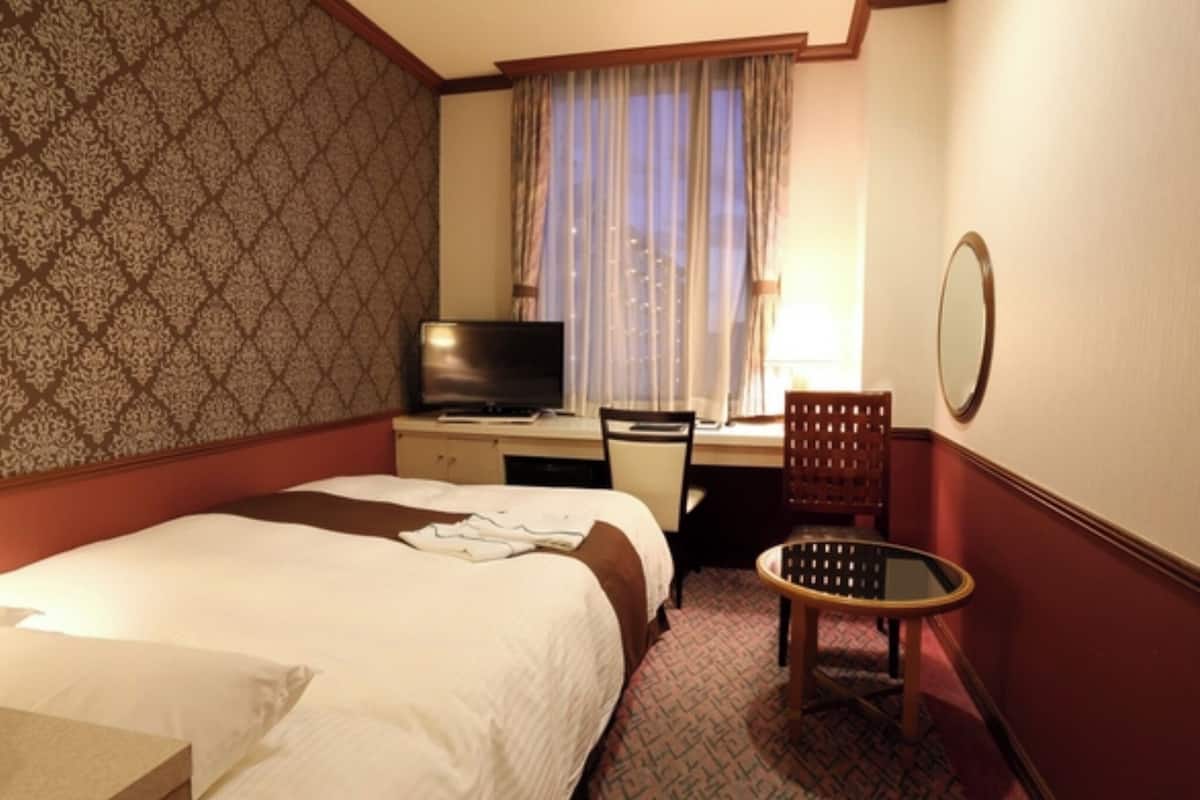 Ein Hotelzimmer mit Bett, Schreibtisch mit Fernseher, Stuhl und kleinem Tisch.