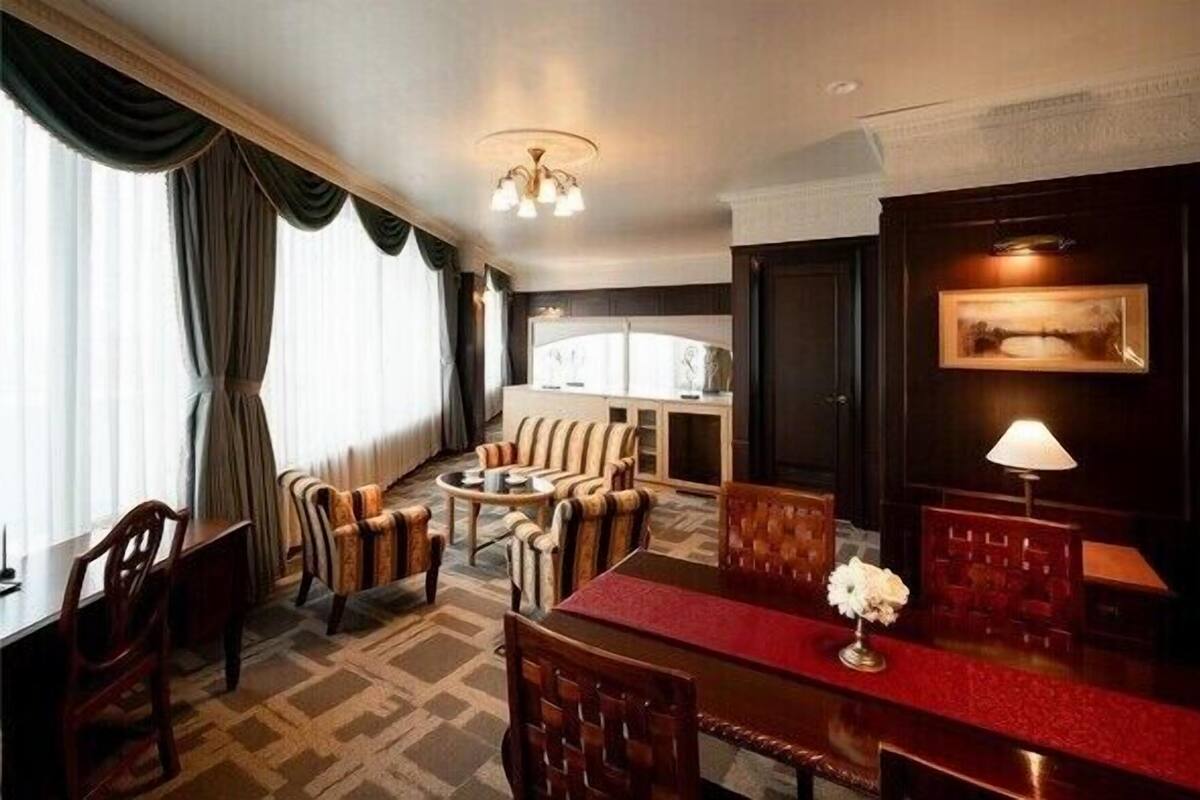 Ein Hotelzimmer mit Essbereich, einer Sofagarnitur, einem Kronleuchter und einem gerahmten Bild an der Wand.